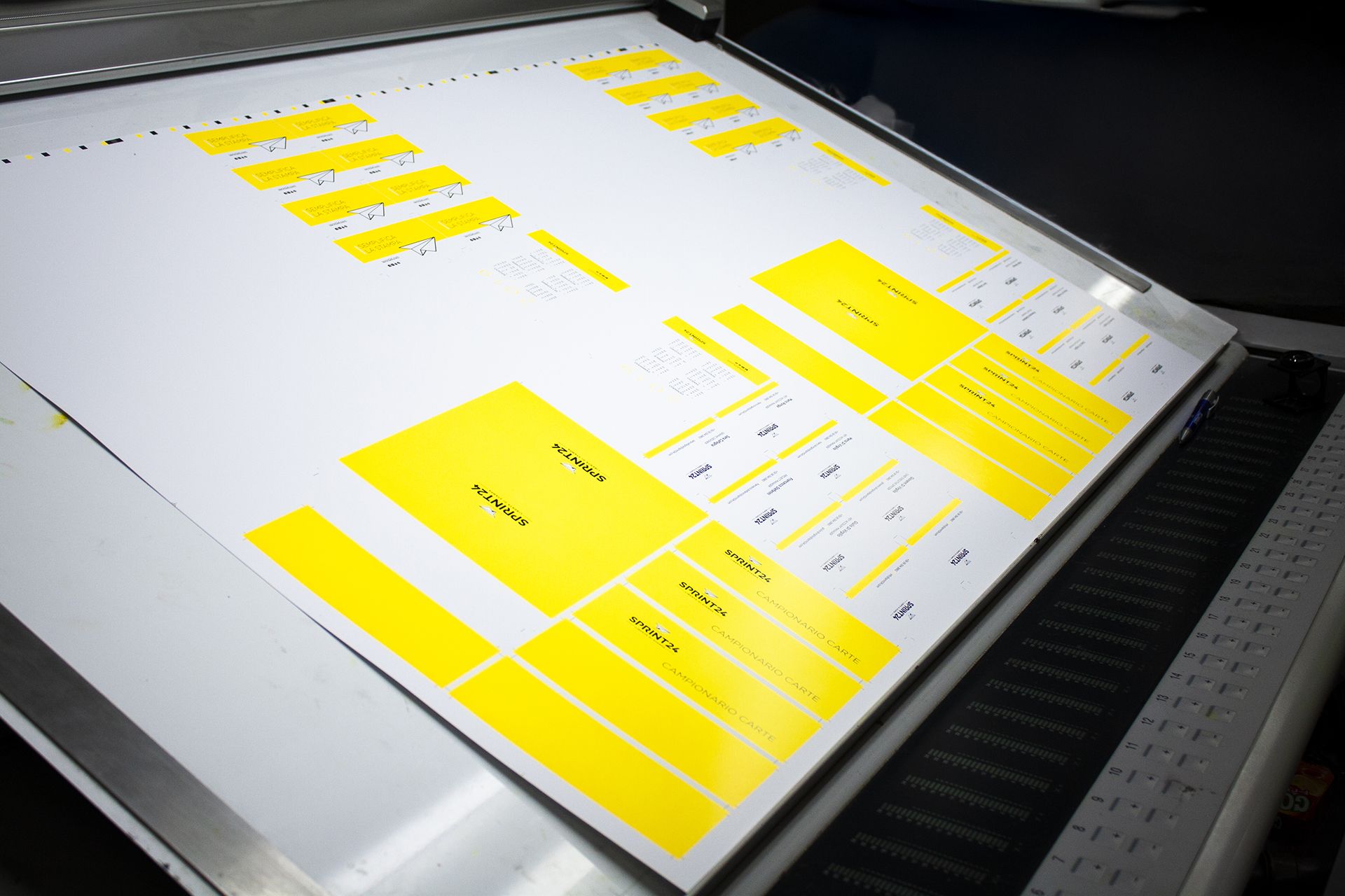 Une feuille d'impression grand format avec des blocs de calibration jaunes repose sur une machine d'impression numérique professionnelle chez Sprint24. Cette image représente le processus d'impression offset et numérique de haute qualité au cœur des services d'imprimerie en ligne de Sprint24. Nos machines de pointe garantissent une précision colorimétrique et des résultats constants pour tous les…