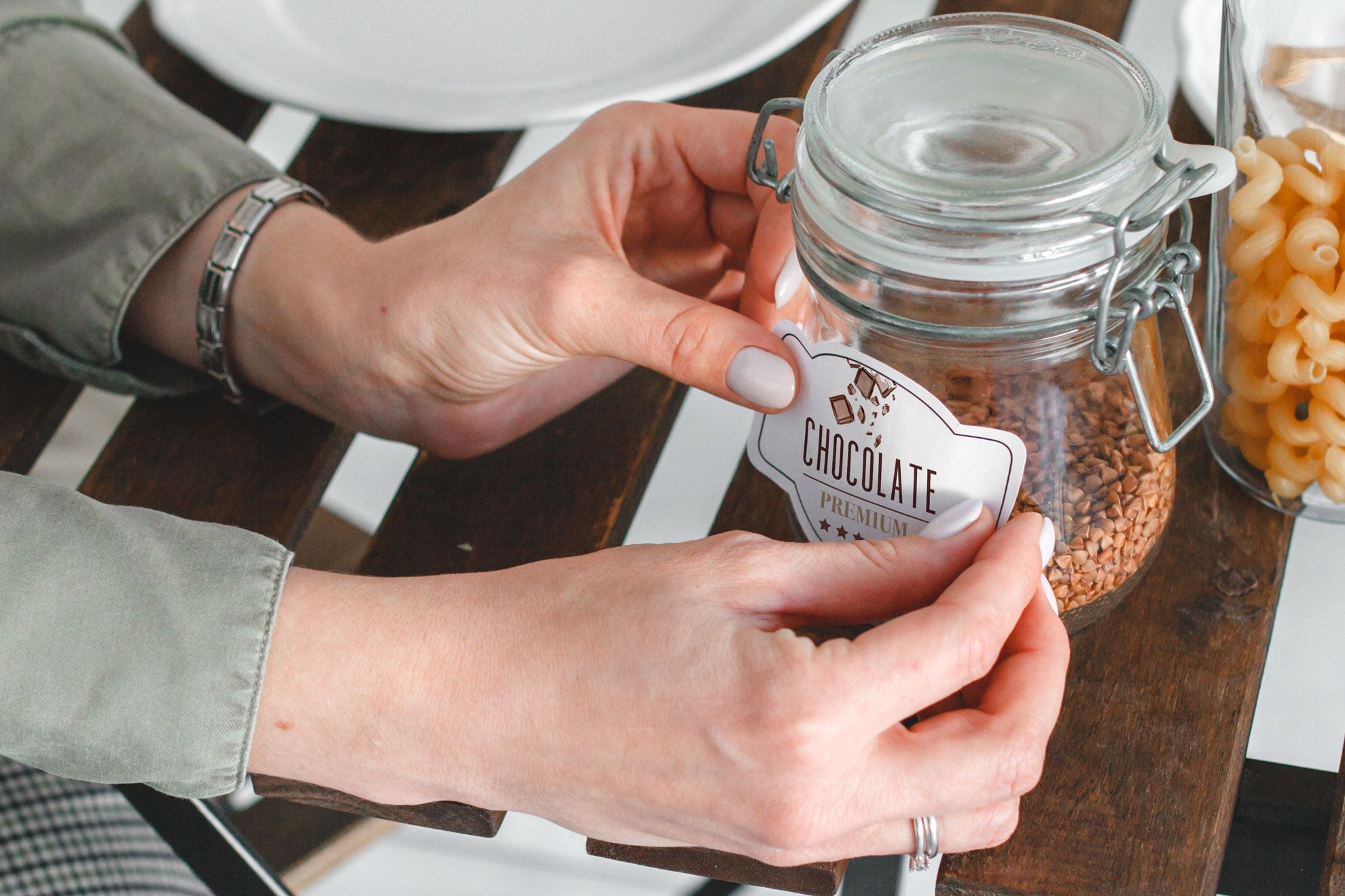 Mains tenant un bocal en verre avec un autocollant de forme. Autocollants forme personnalisee pour bocaux conteneurs et produits toutes tailles branding. Sprint24.