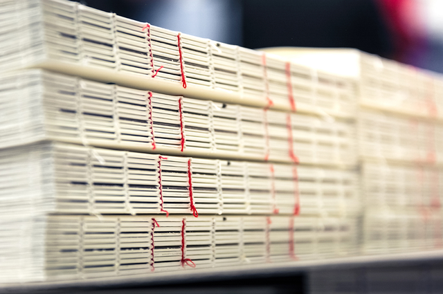 Blocs livres avec fil rouge apparent sur étagère production. Technique artisanale pour éditions prestige Sprint24.