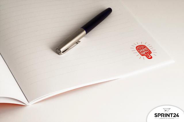 Cahier agrafé premium avec pages blanches et branding rouge. Double agrafage et pelliculage mat.