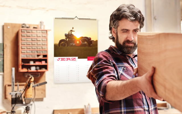 Homme affichant un calendrier mural personnalise avec photos dans bureau domicile. Sprint24.