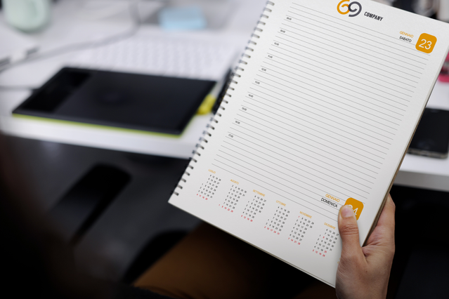 Main tenant agenda quotidien spirale ouvert logo G9 orange timbro data et mini-calendrier. Sprint24.