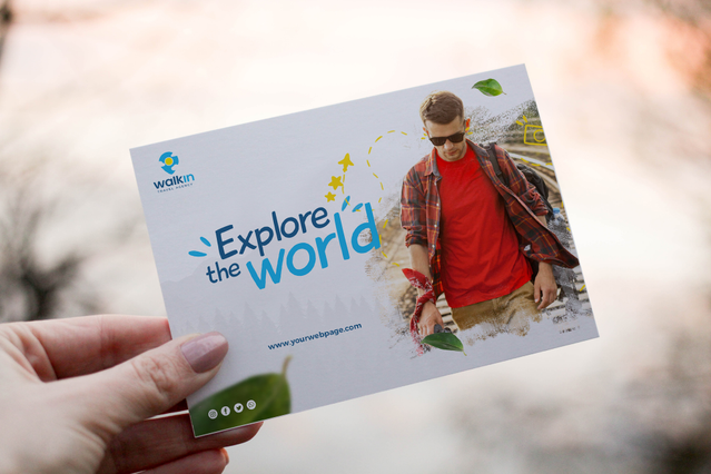 Main tenant carte postale voyage Walkin Explore the World et photo homme chemise rouge. Sprint24.