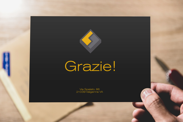 Main tenant carte remerciement noire Grazie logo diamant dore sur bureau bois. Fedrigoni Sprint24.