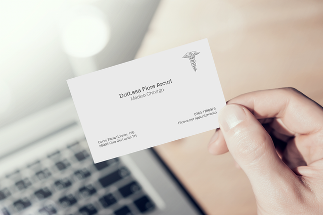 Main tenant carte visite blanche Dott.ssa Flora Accuri Medico Chirurgo avec logo caducee. Sprint24.