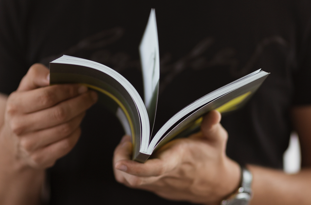 Mains tenant ouvert un livre de poche broche imprime professionnellement. Sprint24.