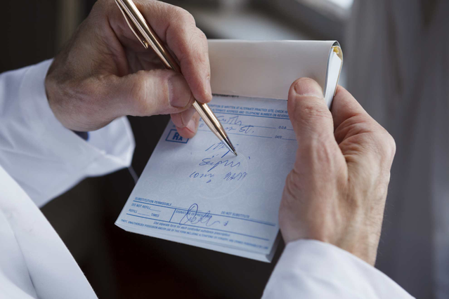 Médecin écrivant sur carnet ordonnances personnalisé avec stylo doré. Carnets brandés médecins Sprint24.