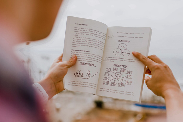 Personne tenant ouvert un guide imprimé avec contenu éducatif Guides imprimes professionnels instructions claires et contenu visuel pour manuels. Sprint24.