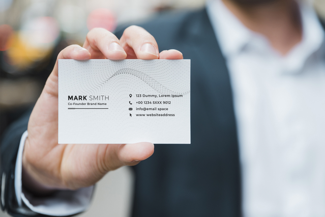 Professionnel tenant une carte de visite blanche avec coordonnées Cartes de visite premium design epure et moderne coordonnees claires pour dirigeants. Sprint24.